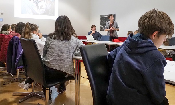 Des enfants écoutent une femme présenter le travail du département communication du DFAE.