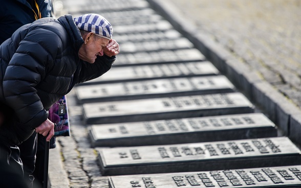 A Holocaust Survivor is looking at memorial stones of victims.