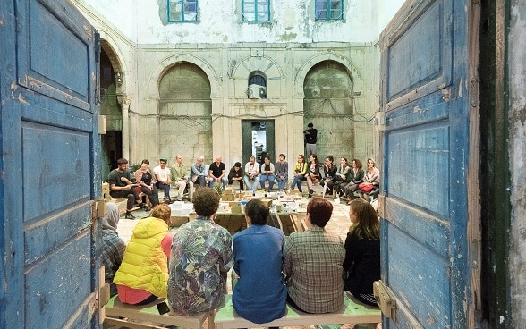 A group of young people sit in a circle in the inner courtyard of a building during the Dream City festival in Tunis.