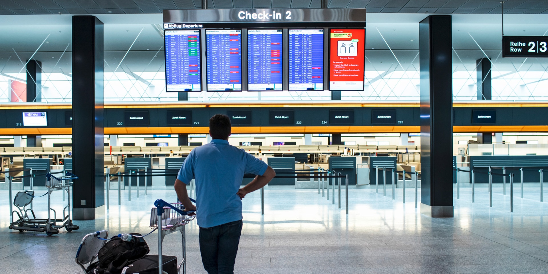  A man studies the departure schedule in the departure hall of an airport. 