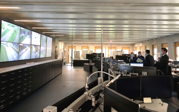 Bundesrat Cassis steht im Steuerungsraum der kantonalen Notfallzentrale und blickt auf Bildschirme an der Wand.
