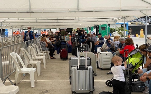 I viaggiatori aspettano in una tenda sull'asfalto dell'aeroporto di Lima, in Perù, prima di imbarcarsi sul volo per Zurigo.