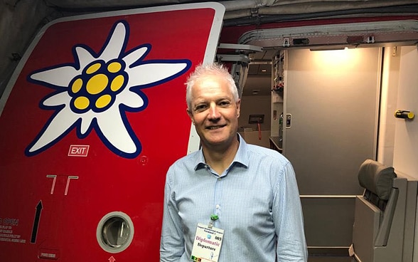 L'ambassadeur suisse au Myanmar, Tim Enderlin, se tient à la porte de l'avion Edelweiss à Yangon. Un Edelweiss est peint sur la porte.