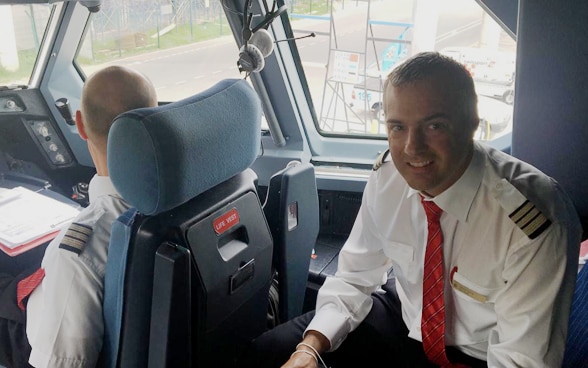 Des membres de l’équipe de pilotage sont assis dans le cockpit de l’avion qui prendra bientôt le départ pour la Suisse. 