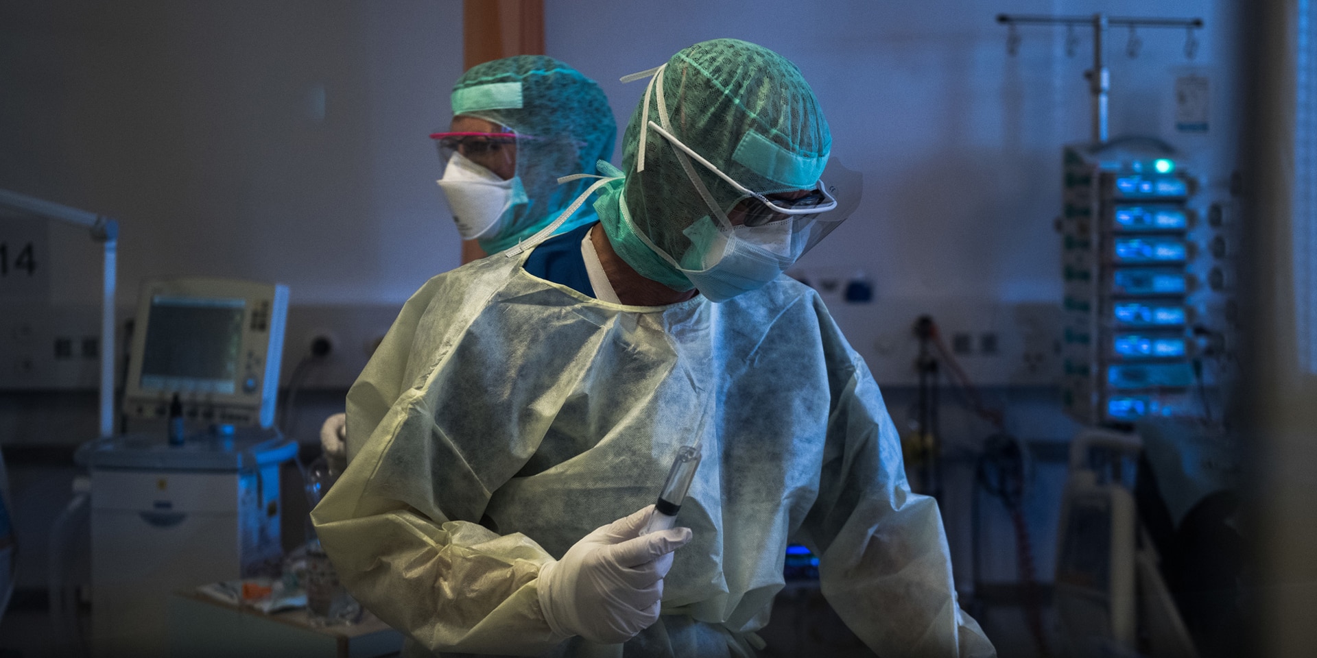 Due persone con una tuta protettiva utilizzano apparecchiature mediche.