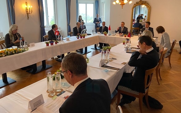 Les représentants des quatre pays et leur délégation assis autour d’une table discutent.