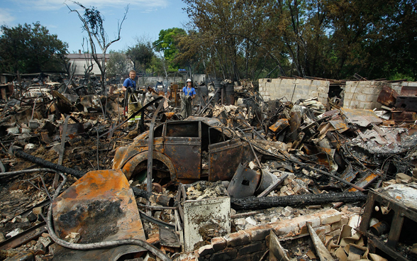  Two men stand in a field of rubble. 