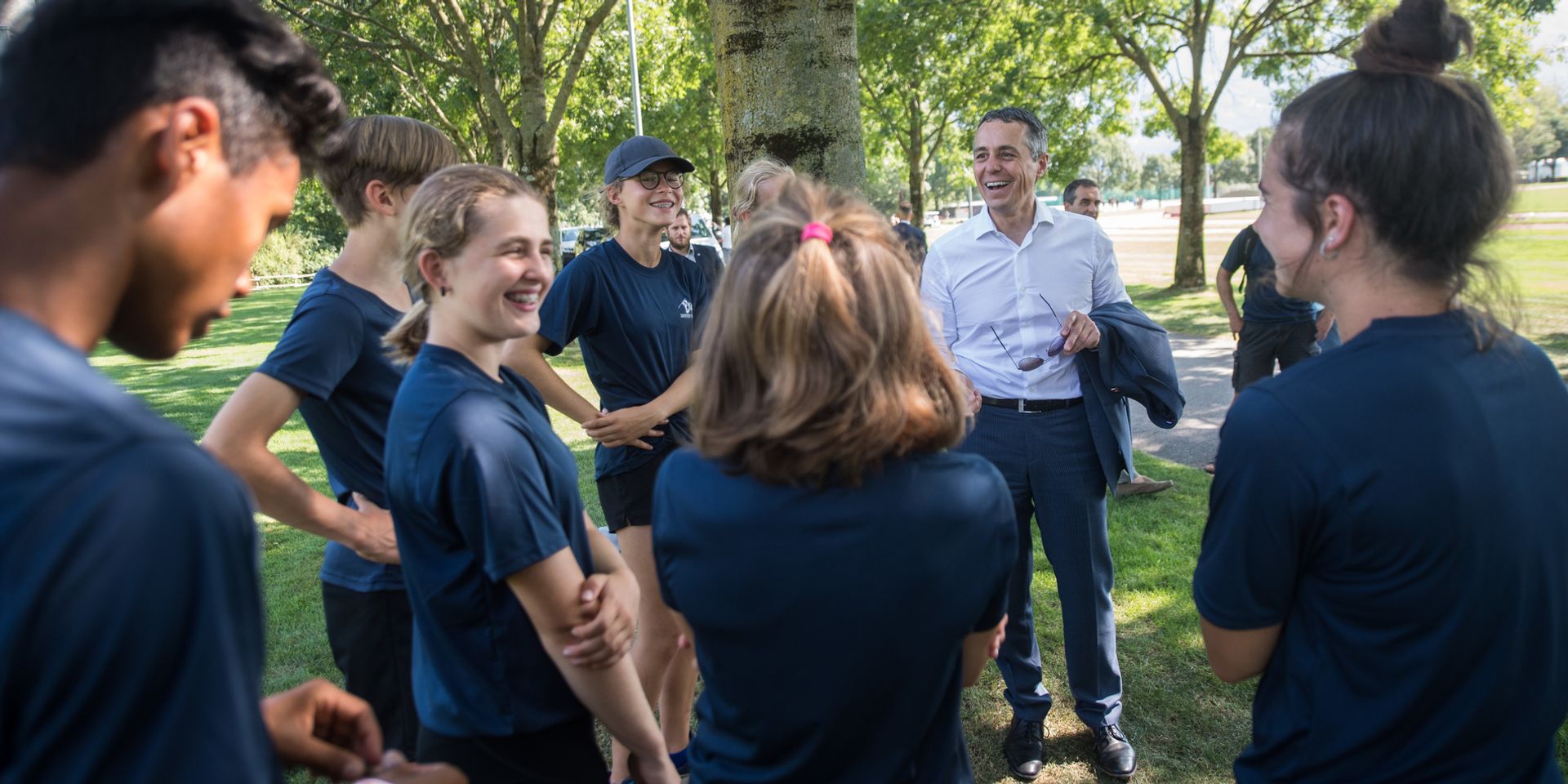 Bundesrat Ignazio Cassis im Gespräch mit Leichtathletinnen und Leichtathleten beim Training. 