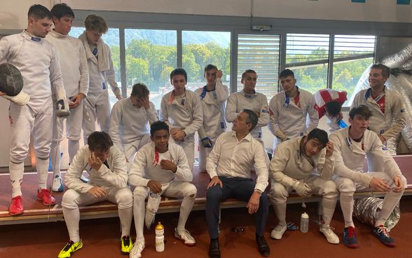 Federal Councillor Ignazio Cassis sits on a bench together with fencers in the school gym. 