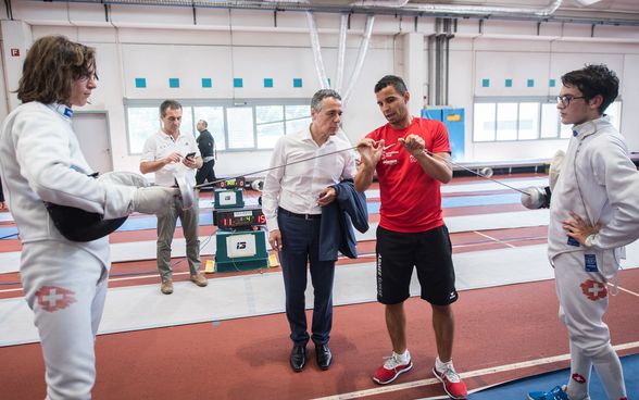 Le conseiller fédéral Ignazio Cassis s'entretient avec un escrimeur dans le gymnase du centre sportif.