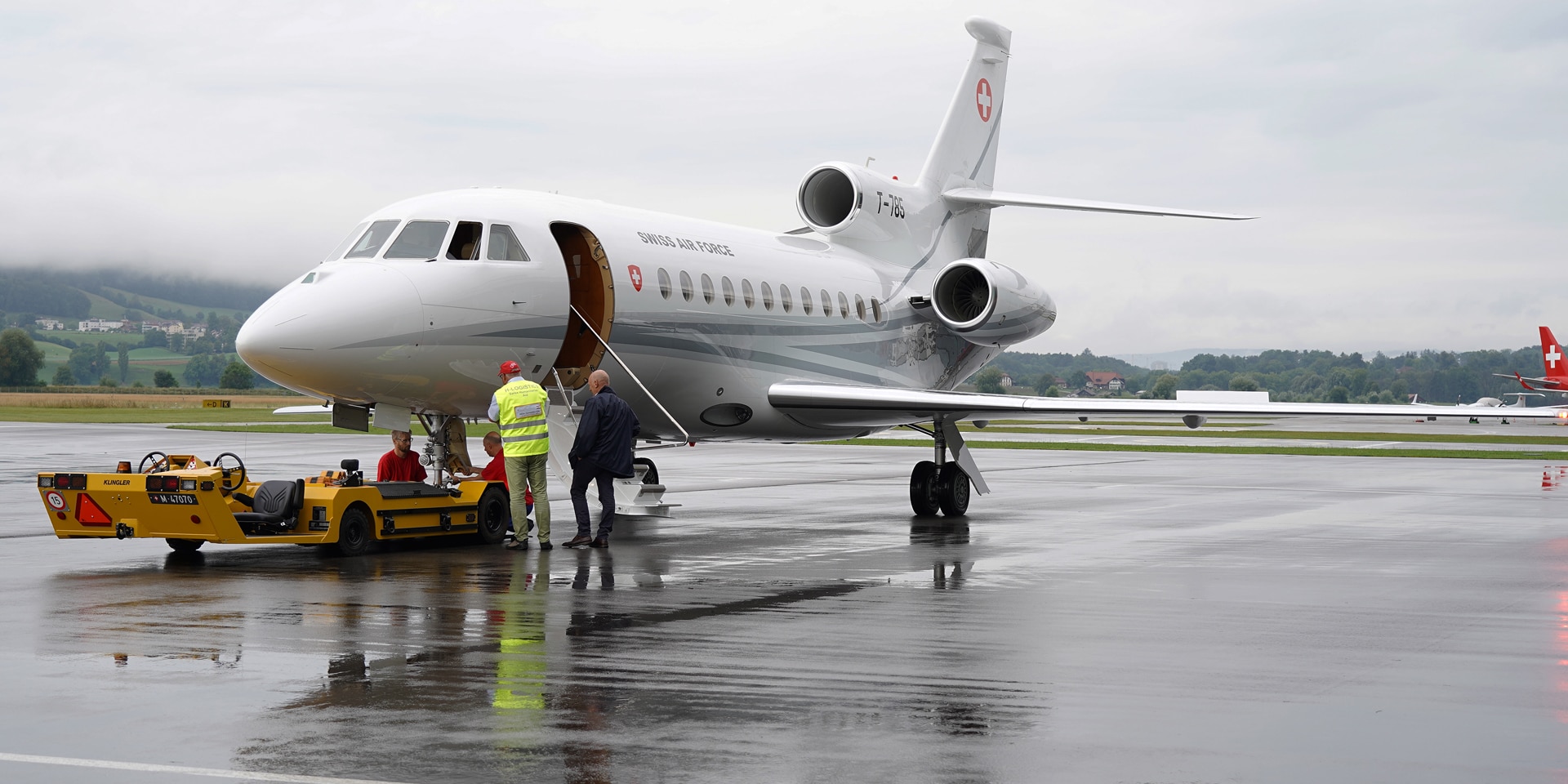 Two men standing in front of an aircraft on the tarmac at Bern-Belp airport. 