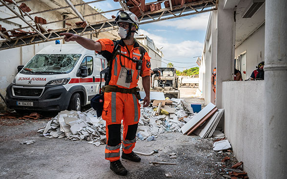 An expert from the Swiss Humanitarian Aid Unit is standing in the debris of a hospital.