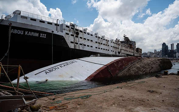 Dans le port de Beyrouth, un navire a un côté coulé dans l'eau.