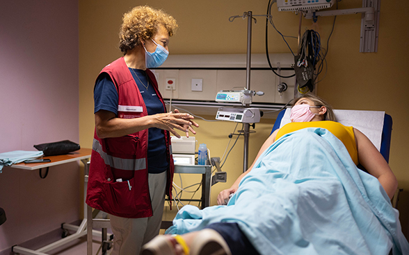  Professor and head doctor Irene Hösli talks to a woman lying in bed. 