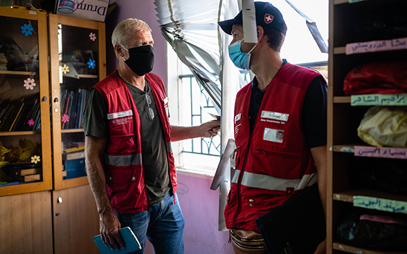 Due esperti del Corpo svizzero di aiuto umanitario discutono in un'aula distrutta.