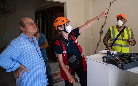 Engineer Regina Wenk shows damages on the wall to a resident.