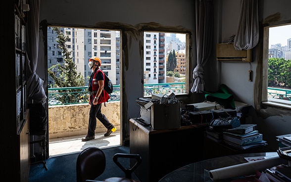 Vista su un appartamento distrutto e senza finestre. L'ingegnere Regina Wenk, sul balcone, si consulta con un membro delle autorità mentre ispeziona l’edificio.  