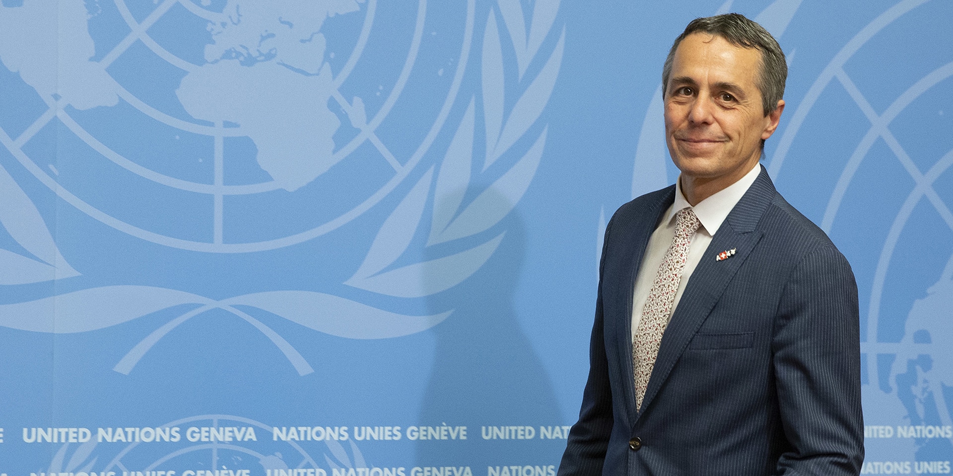 Federal Councillor Ignazio Cassis stands in front of a podium, behind him a wall with the UN logo.