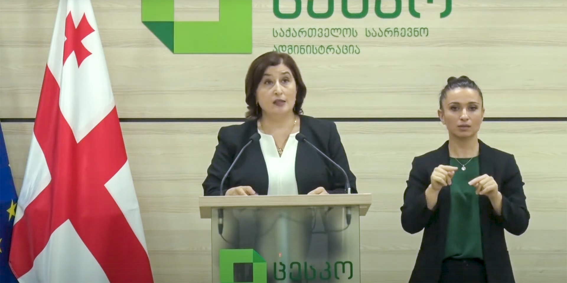 Die Leiterin der Zentralen Wahlkommission in Georgien steht am Pult, neben ihr eine Spezialistin für Gebärdensprache.