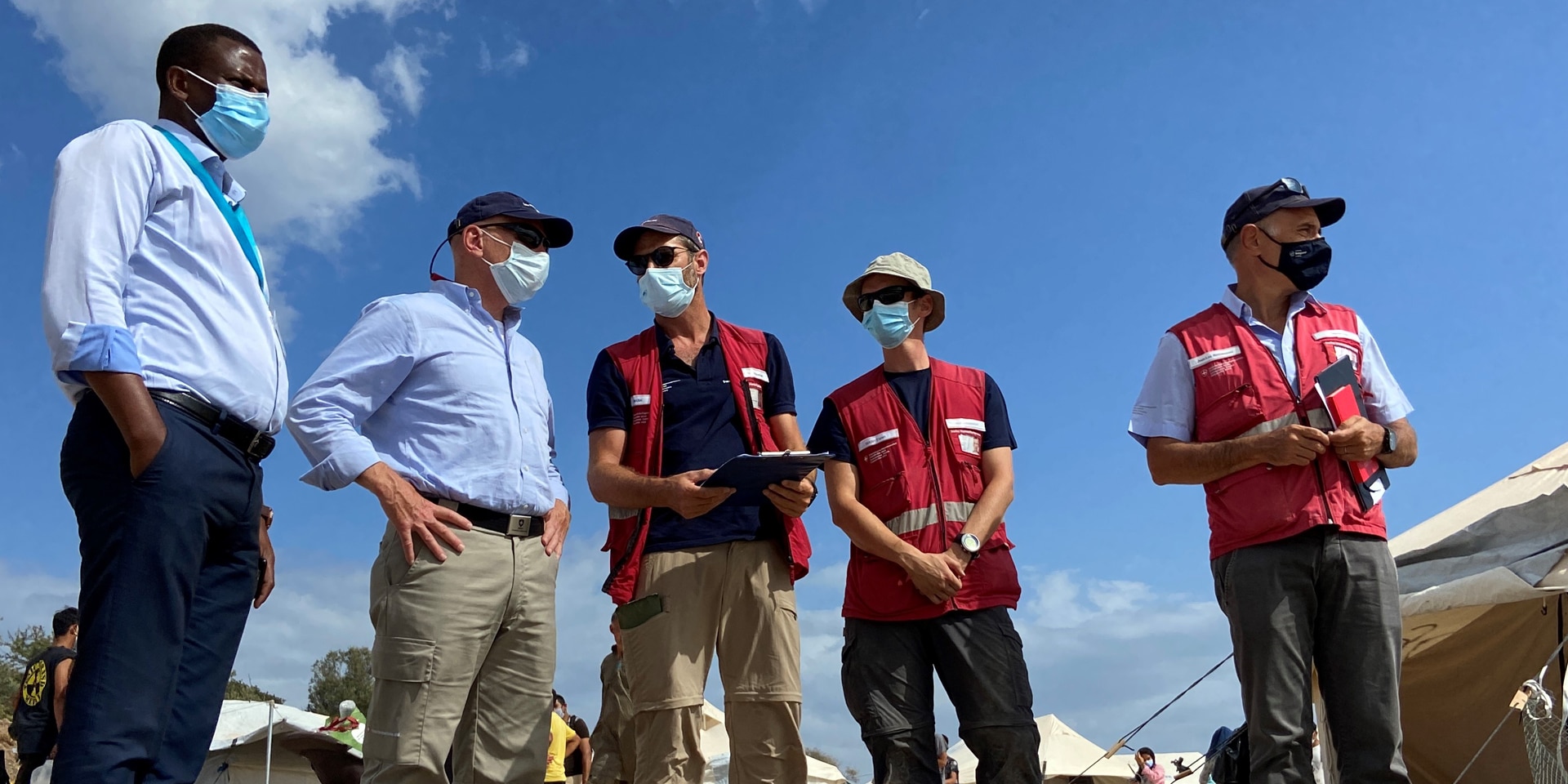 Le chef de l’aide humanitaire suisse Manuel Bessler s’entretient avec des membres du Corps suisse d’aide humanitaire et Spiros Habimama directeur général adjoint du camp de Lesbos lors d’une visite sur le terrain.