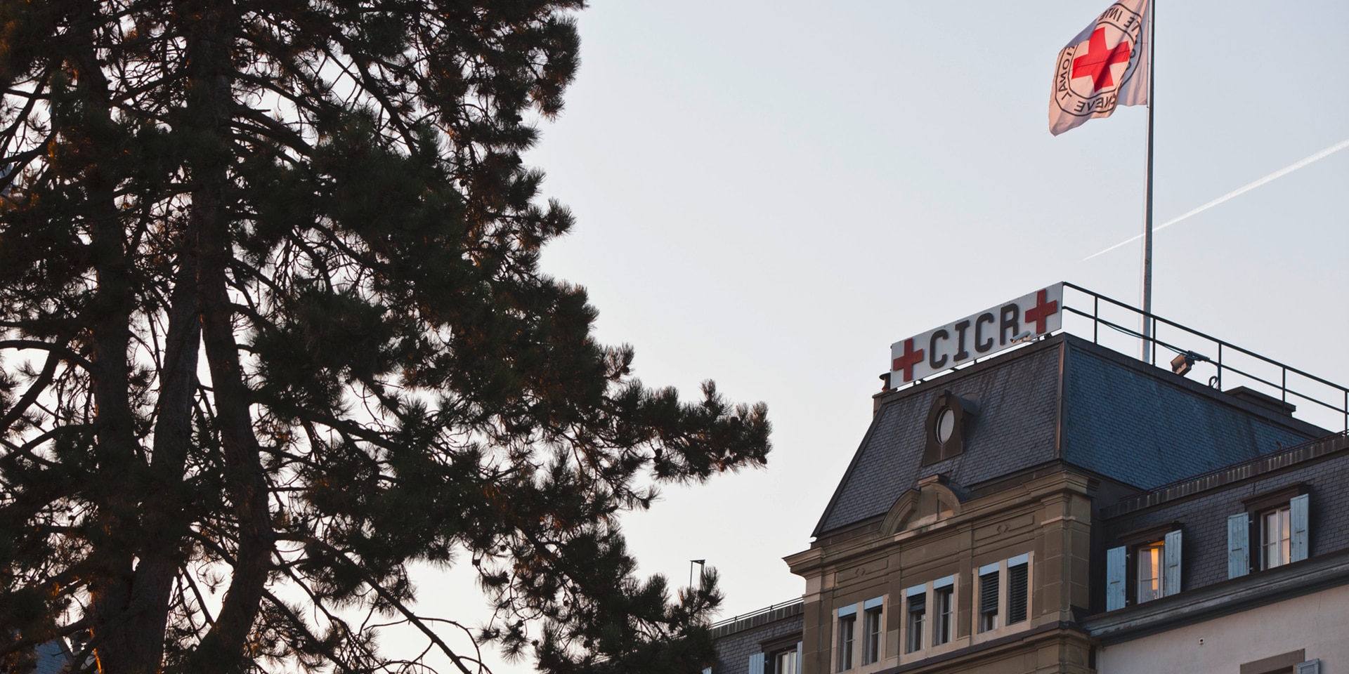 Sur le toit du bâtiment du CICR, un panneau et un drapeau affichent l’emblème de l’organisation humanitaire, la fameuse croix rouge sur fond blanc.