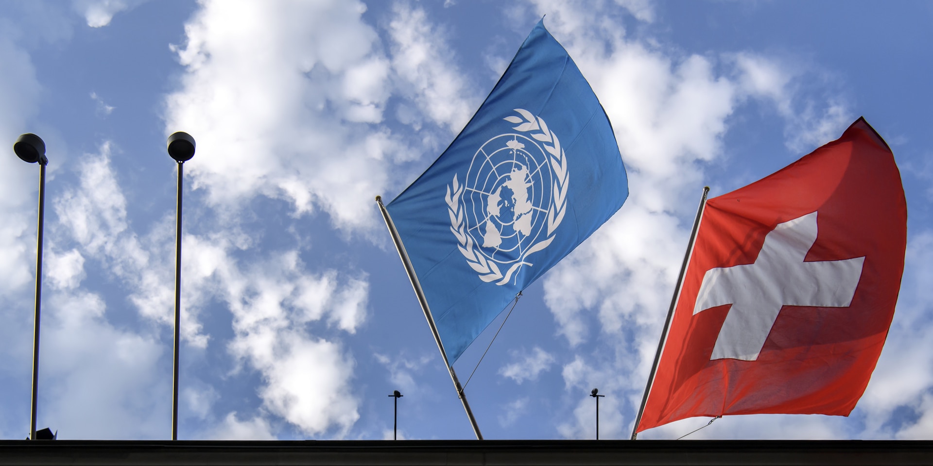 The UN flag, on the left, and the Swiss flag, on the right, flying above the Federal Palace.