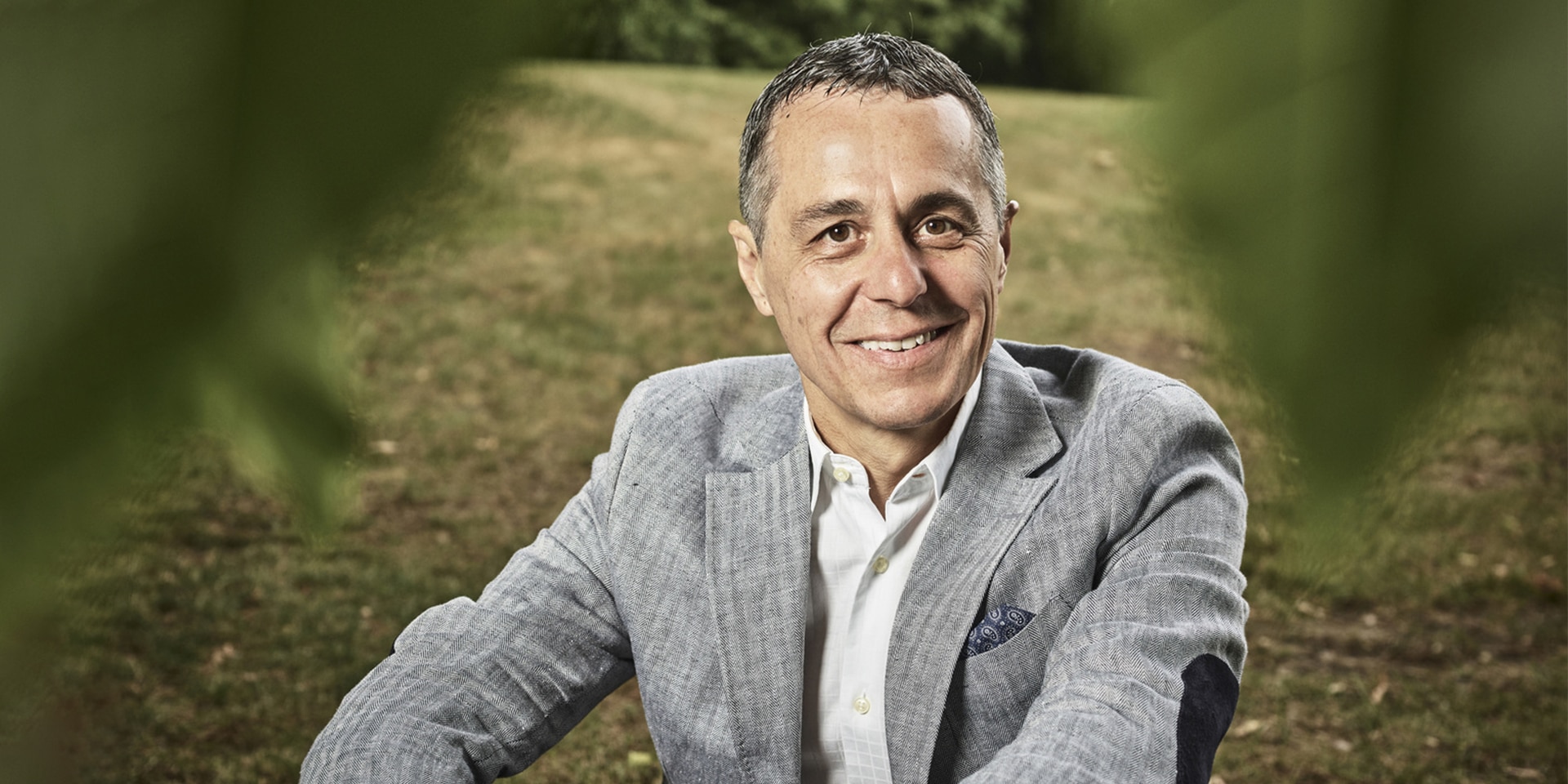 Portrait du conseiller fédéral Ignazio Cassis assis dans une prairie. 