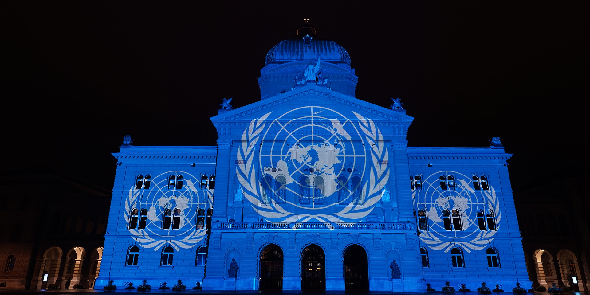 The United Nations flag is projected onto the front of the Federal Palace.