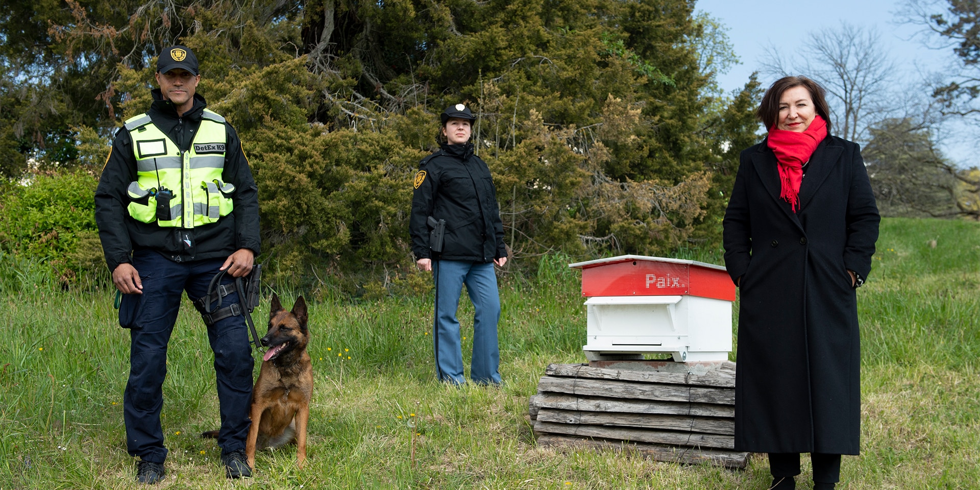 On the lawn of the UN building Anne-Lise Favre Pilet stands next to two UN agents and a bomb-sniffing dog. 