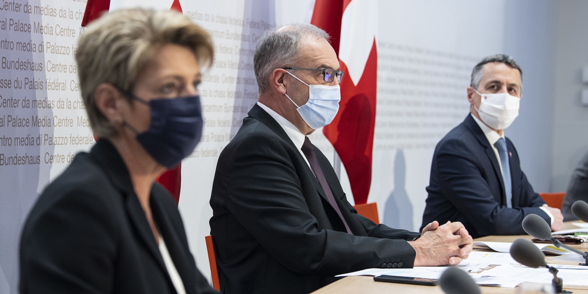  Le président de la Confédération Guy Parmelin, le conseiller fédéral Ignazio Cassis et la conseillère fédérale Karin Keller-Sutter sont assis devant les pupitres de l’estrade du centre de presse à Berne.