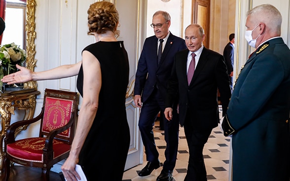 Bundespräsident Guy Parmelin und der russischen Präsidenten Wladimir Putin kommen durch eine Türe in einen Raum.