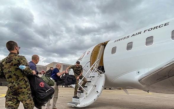  Plusieurs personnes chargent des bagages dans un avion.   