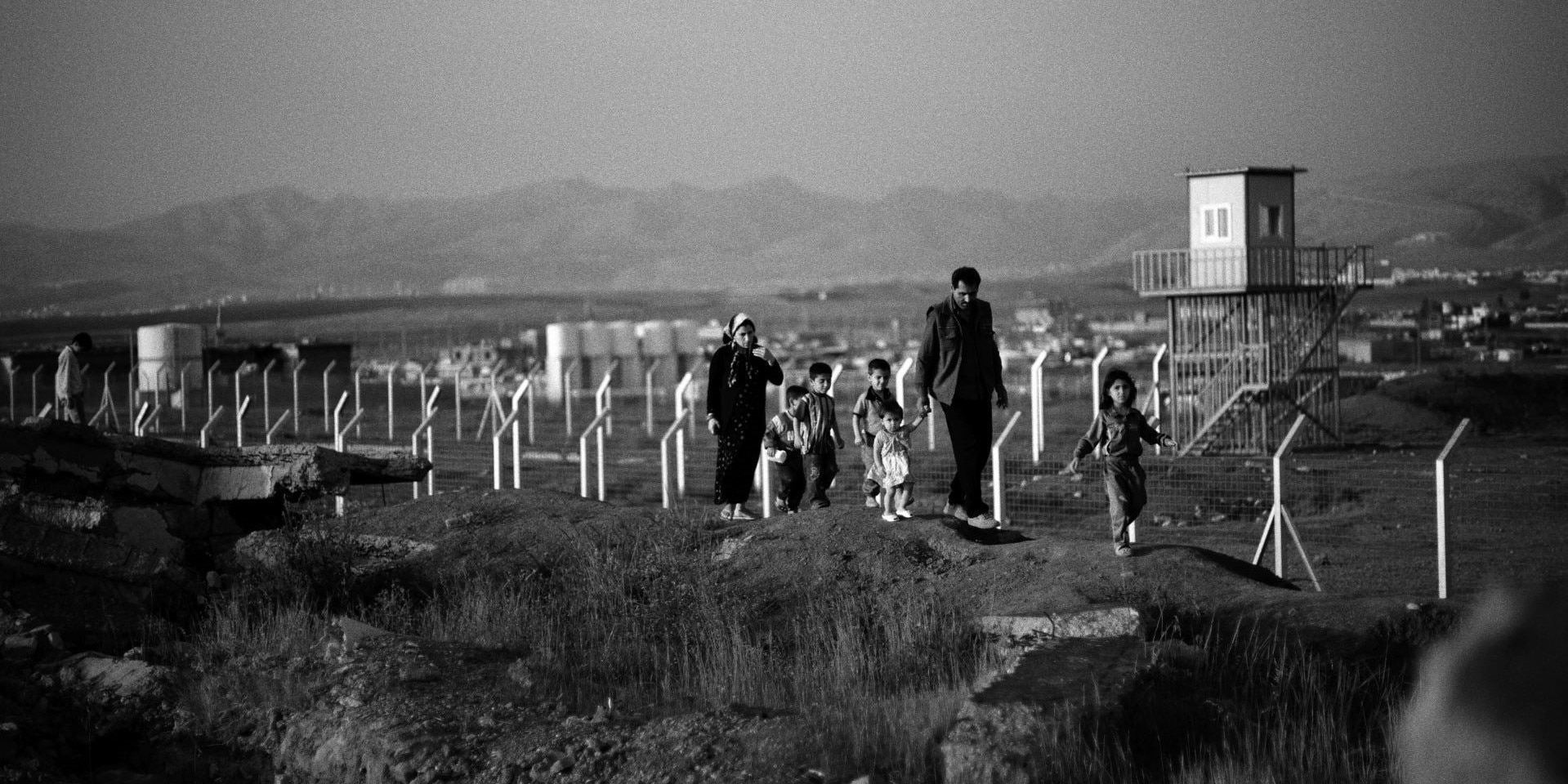 Une famille irakienne traverse un champ qui a été bombardé par des armes à sous-munitions.