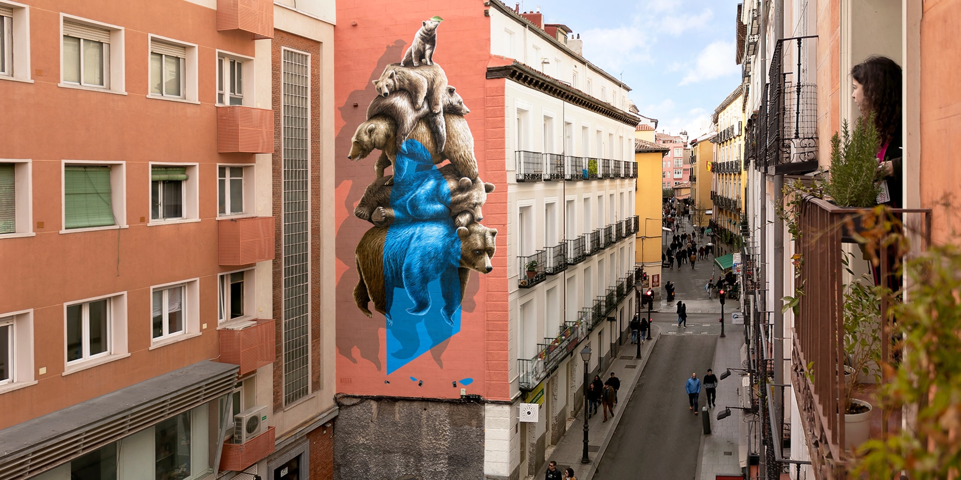 Das Nevercrew-Wandbild  befindet sich in einer Strasse im Zentrum von Madrid. Eine Frau betrachtet das Bild interessiert von ihrem Fenster aus. 