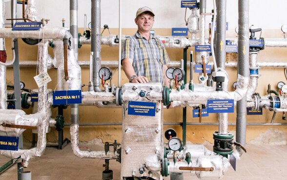  Yevhen Yarovyi stands in front of a new heating system.