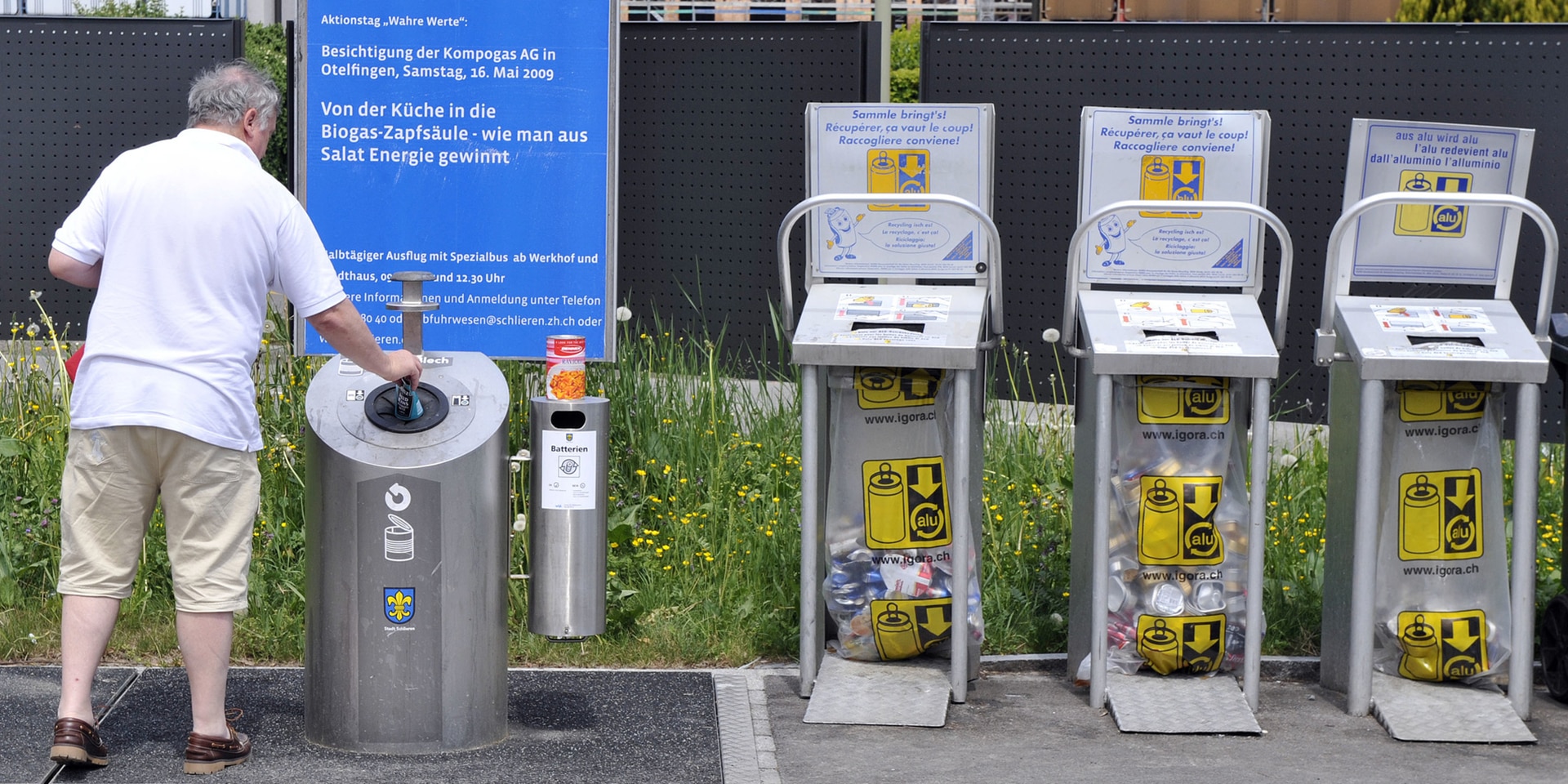 A man recycles a tin can. Three collection points for aluminium drink cans are also pictured. 