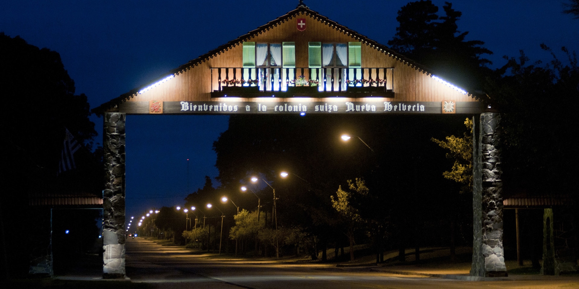 Night scene of a street and a portal depicting a chalet with Swiss motifs.  