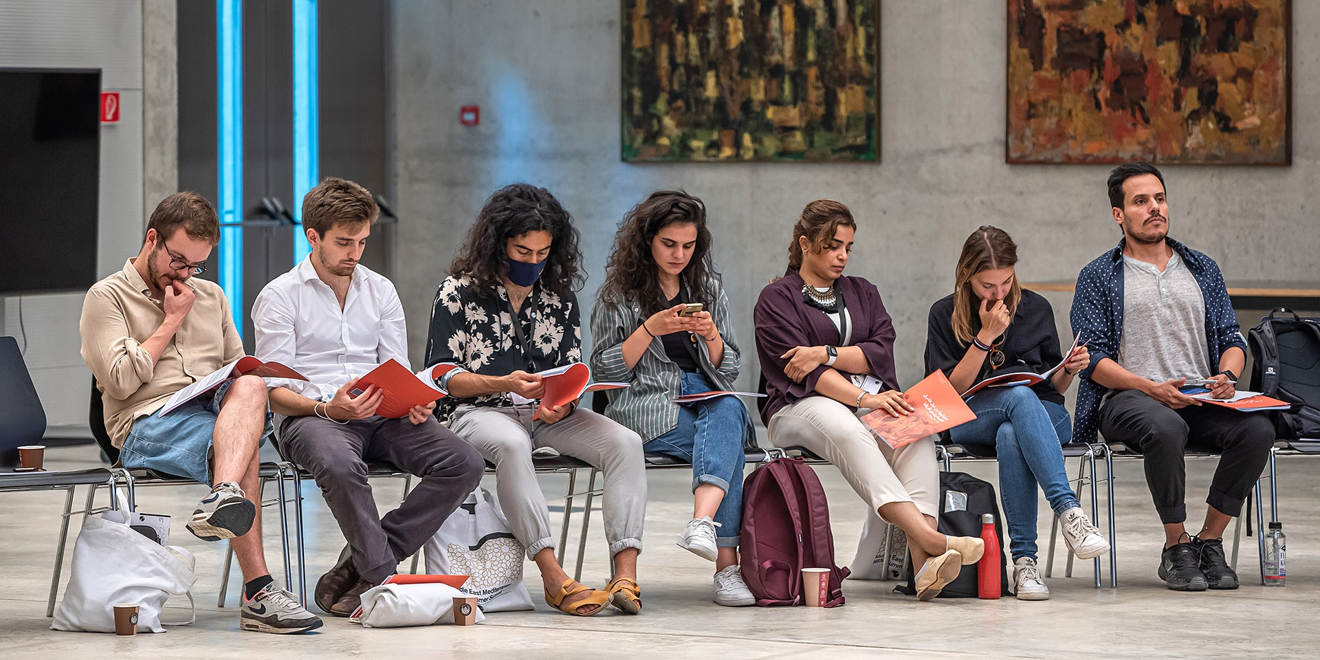 Sept jeunes sont assis sur des chaises. Ils lisent la stratégie MENA du DFAE.