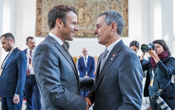 Bundespräsident Cassis und der französische Präsident Emmanuel Macron stehen sich gegenüber und sprechen miteinander.