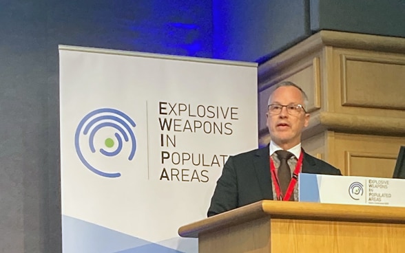 Ambassador Simon Geissbühler speaks at a lectern. 