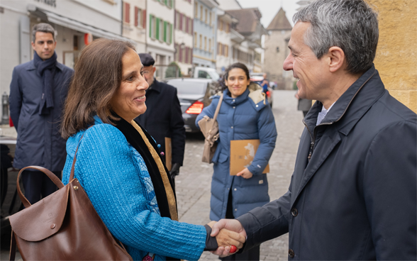 Federal Councillor Cassis and Foreign Minister Urrejola Noguera shake hands. The houses of Murten can be seen in the background.