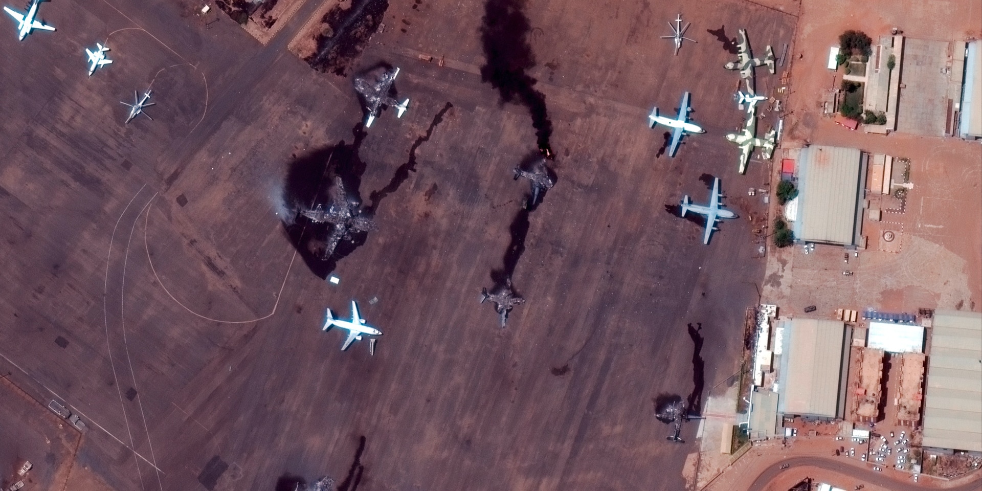Bild von oben auf das Flugfeld des Flughafens von Khartum, auf dem mehrere Flugzeuge zu sehen sind. Vier Flugzeuge sind ausgebrannt.
