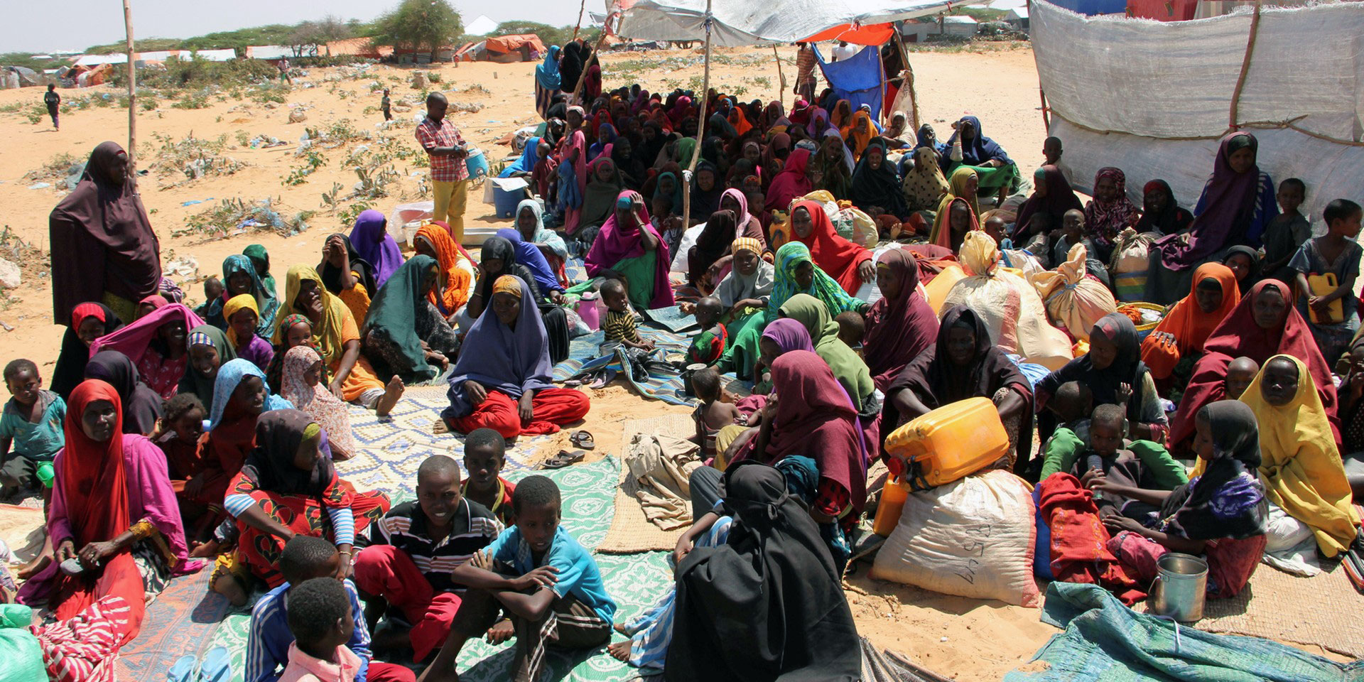 En Somalie, un groupe de personnes déplacées internes attend, assis par terre.