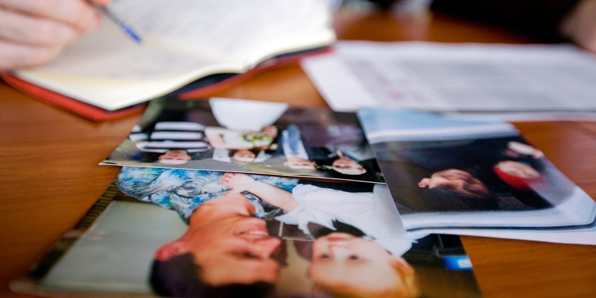 Des photos de famille sont posées sur une table avec en arrière-fond une personne qui rempli un formulaire du CICR.