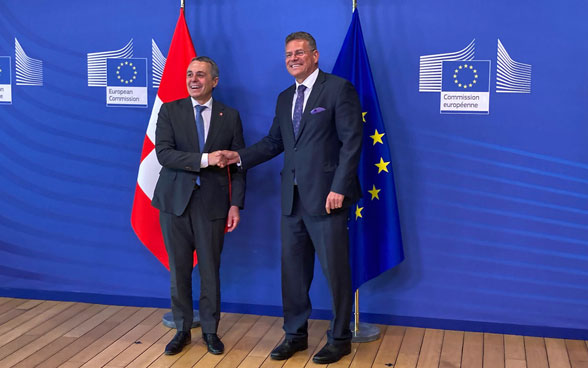 Ignazio Cassis et Maroš Šefčovič se serrent la main. Les drapeaux suisse et européen sont en arrière-fond.