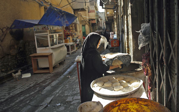 Una donna prepara il pane nelle strade di Baghdad.