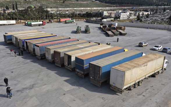Numerous trucks are lined up in a convoy on a road in Syria.