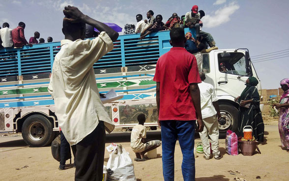 Women and men board a packed lorry in Khartoum.