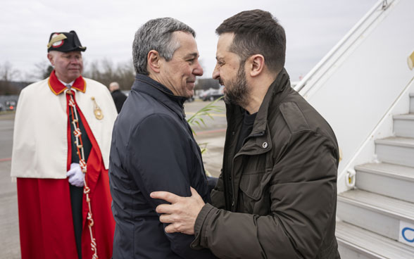 Federal Councillor Cassis warmly welcomes President Zelenskyy. An usher stands in the background.