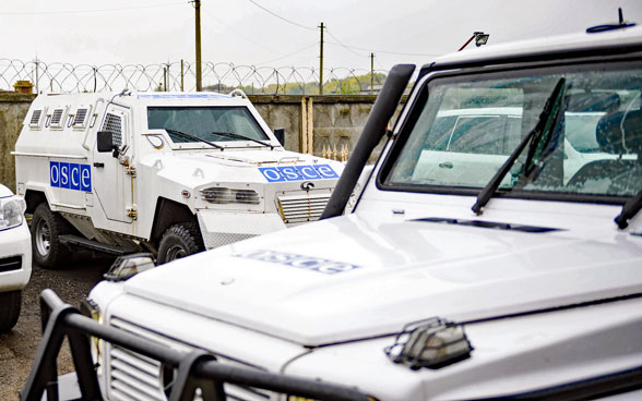Veicoli fuoristrada bianchi dell'OSCE parcheggiati in un parcheggio in una zona di conflitto.